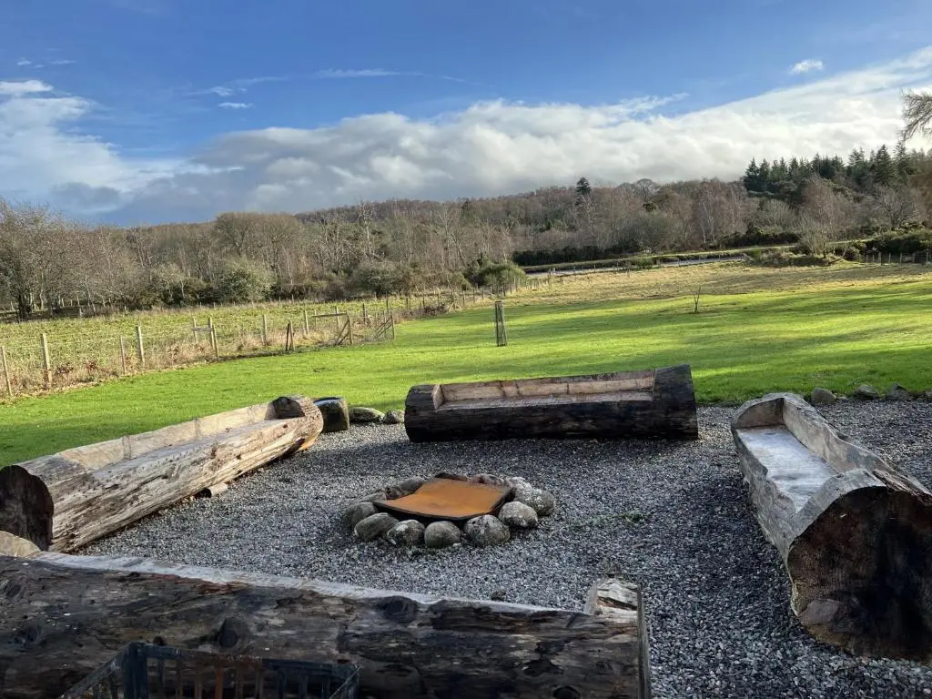 a garden with logs and rocks in a field at Dunaincroy Farmhouse in Inverness