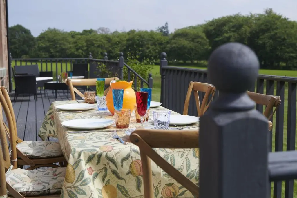 a table with plates and glasses on a patio at Dunaincroy Farmhouse in Inverness