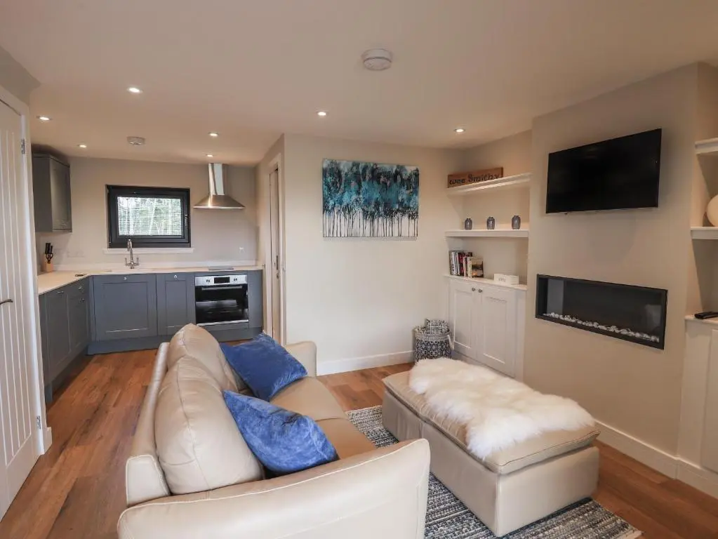 a living room with a white couch and a tv at Wee Smithy in Munlochy