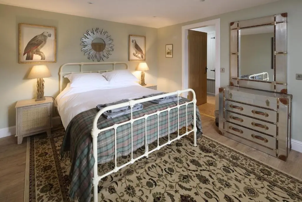 a bedroom with a bed and a dresser and a mirror at Middleton Farmhouse in Inverness