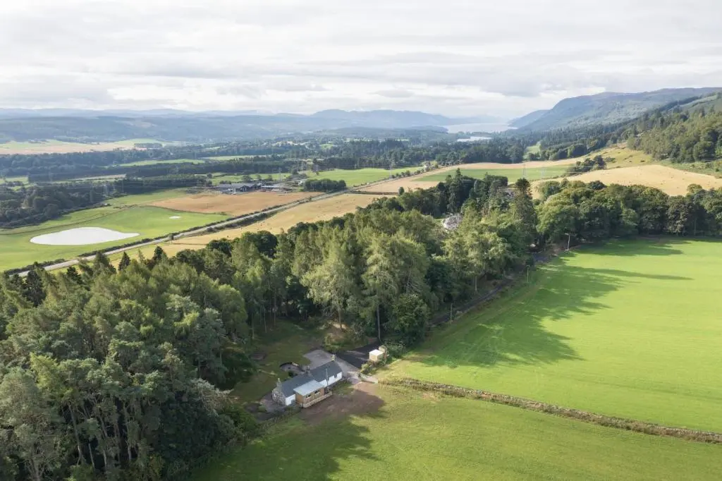 an aerial view of a house in a field with trees at Upper Dunain in Inverness