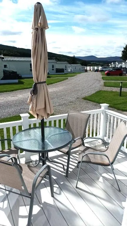 an umbrella sitting on a glass table on a patio at Binka - Luxury 40 x 14ft Lodge in Tain