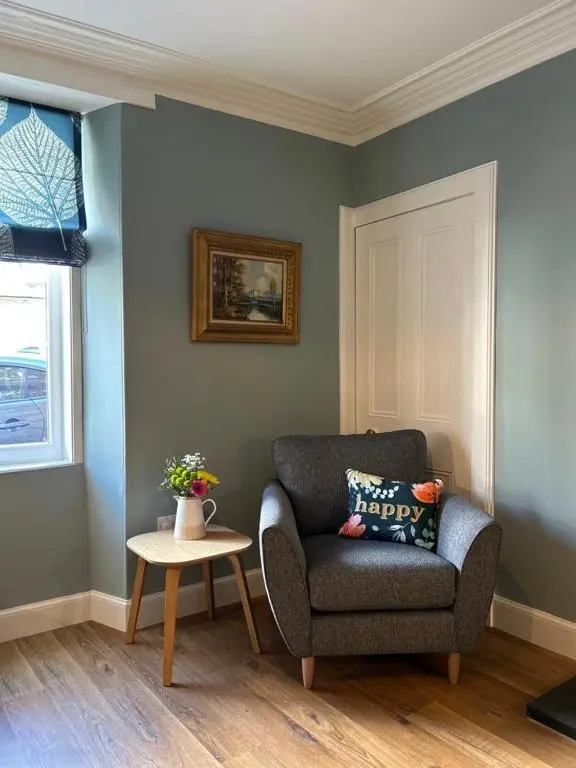 a living room with a chair and a table at The Fiddich Luxury Home in Craigellachie in Craigellachie