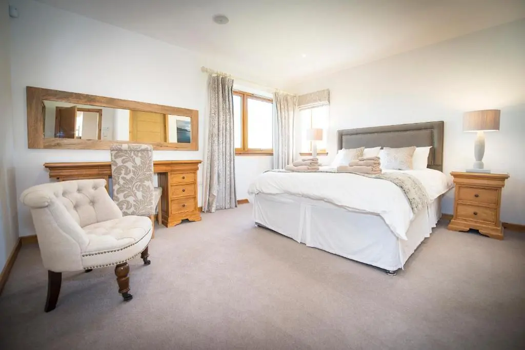 a bedroom with a bed and a chair and a mirror at Atlas in Nairn