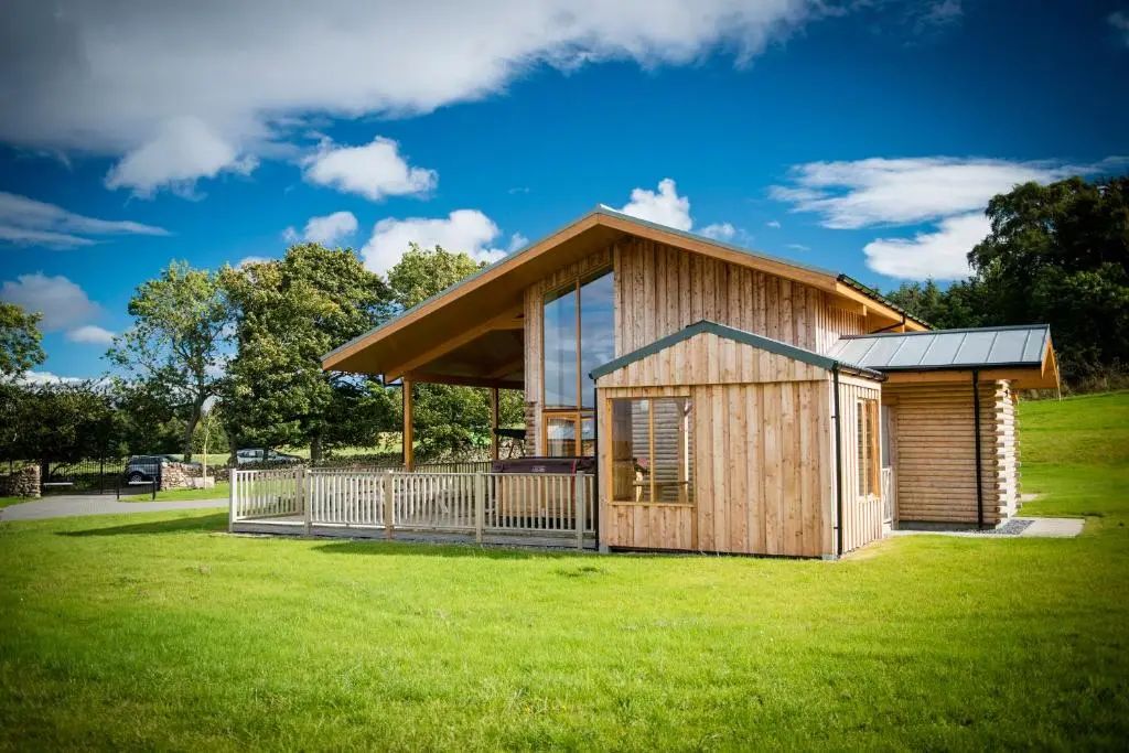 a small wooden cabin with a large grass field at Atlas in Nairn