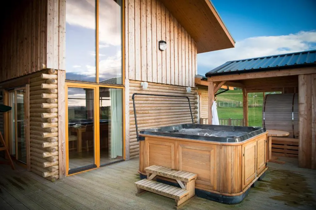 a hot tub on a deck next to a building at Aurae in Nairn