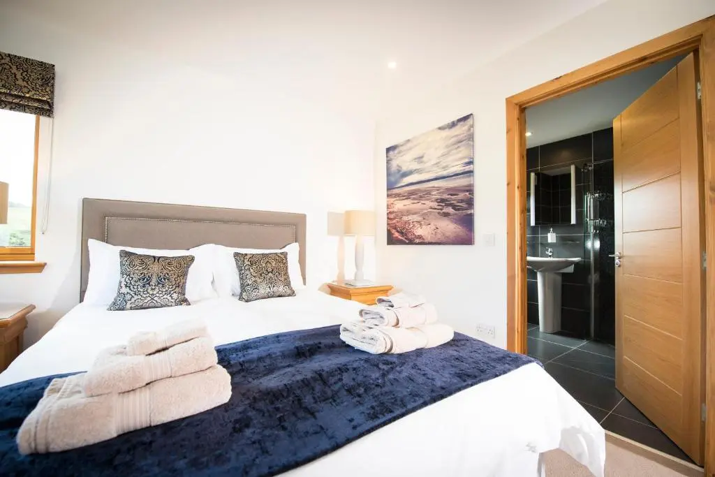 a bedroom with a large bed with towels on it at Aurae in Nairn