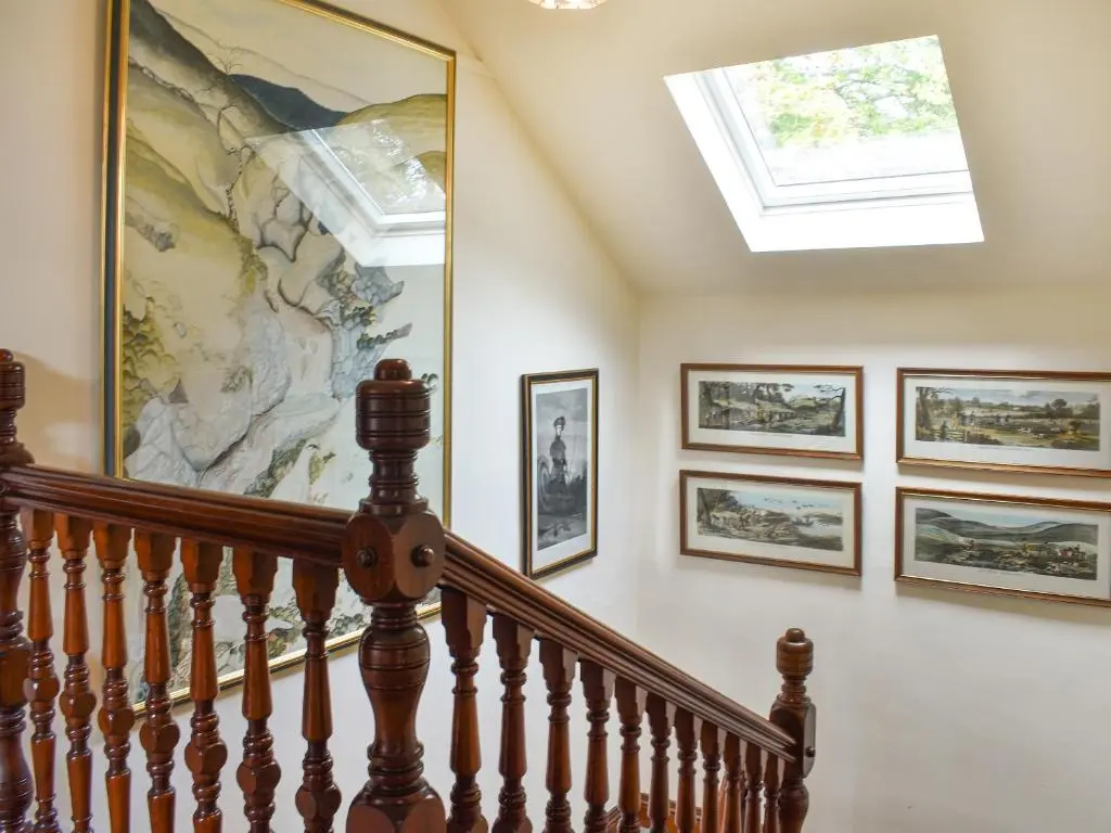 a staircase with a skylight and pictures on the wall at Gleneffock Farmhouse in Tarfside