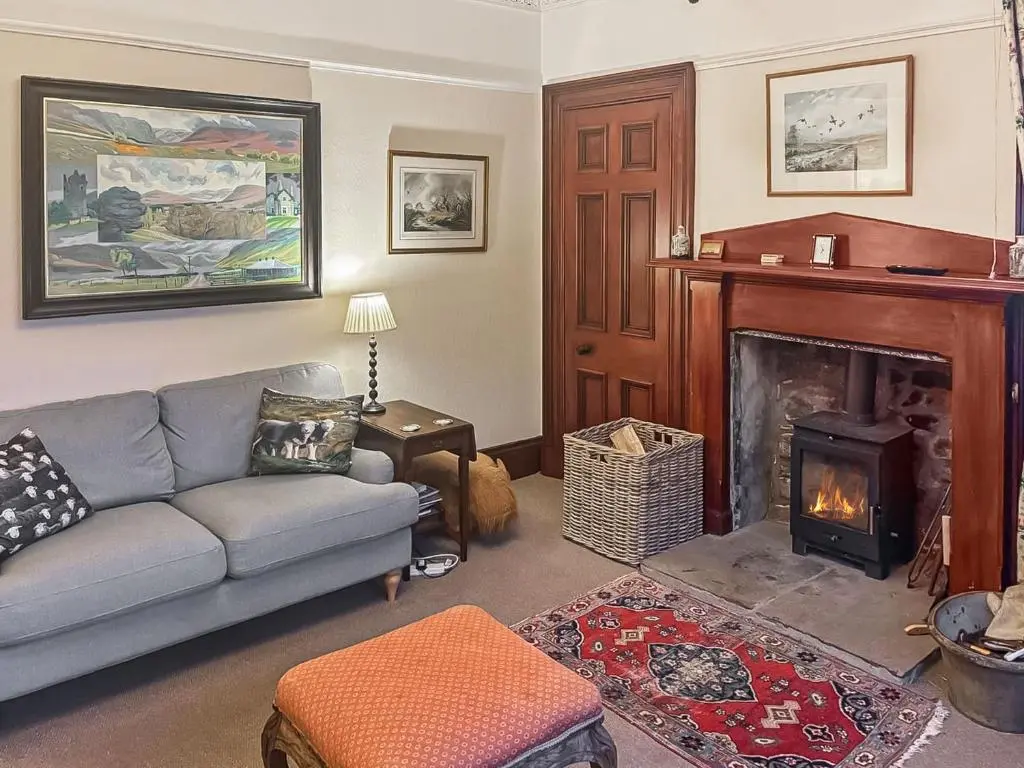 a living room with a couch and a fireplace at Gleneffock Farmhouse in Tarfside