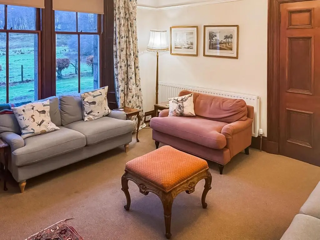 a living room with two couches and a window at Gleneffock Farmhouse in Tarfside