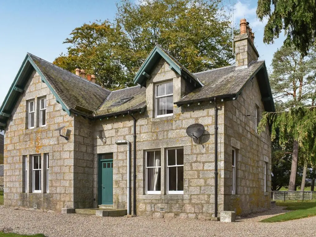 an old stone house with a green door at Gleneffock Farmhouse in Tarfside