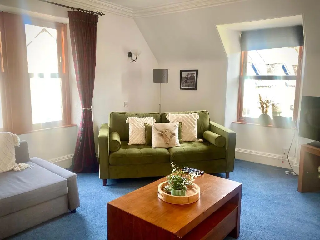 a living room with a green couch and a coffee table at Bruachdryne Braemar Accommodation in Braemar