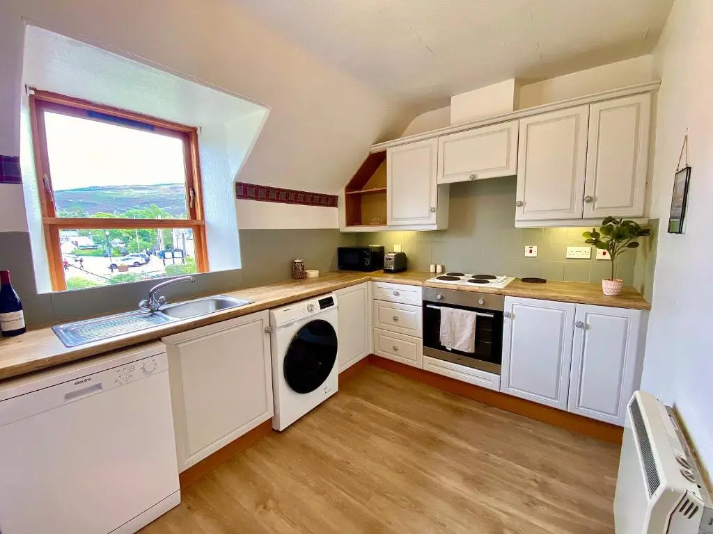 a kitchen with white cabinets and a sink and a window at Bruachdryne Braemar Accommodation in Braemar