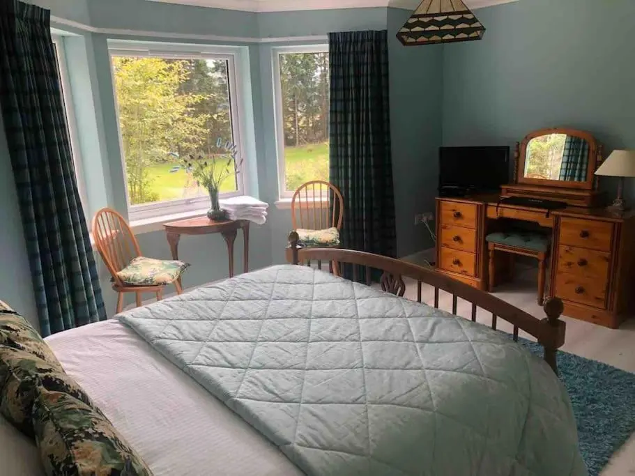a bedroom with a bed and a desk and a window at Cardon House - luxury Highland holiday home in Inverness
