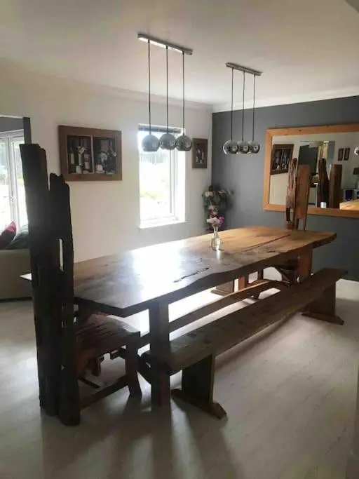 a wooden dining room table with a bench and a table and chairs at Cardon House - luxury Highland holiday home in Inverness