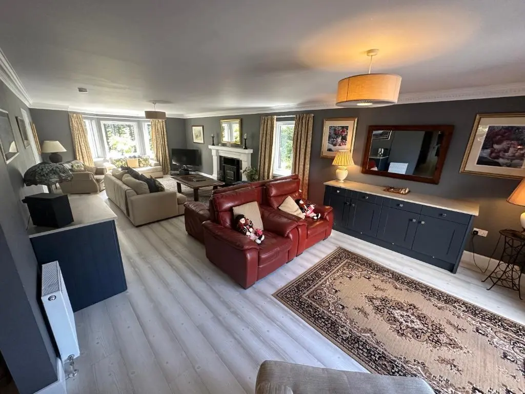 a living room with a red couch and a tv at Cardon House - luxury Highland holiday home in Inverness