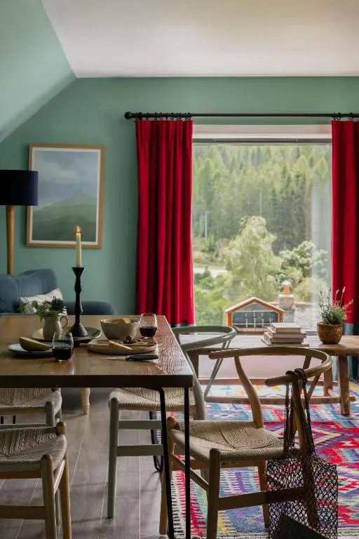 a living room with red curtains and tables and a large window at The Hayloft in Banchory