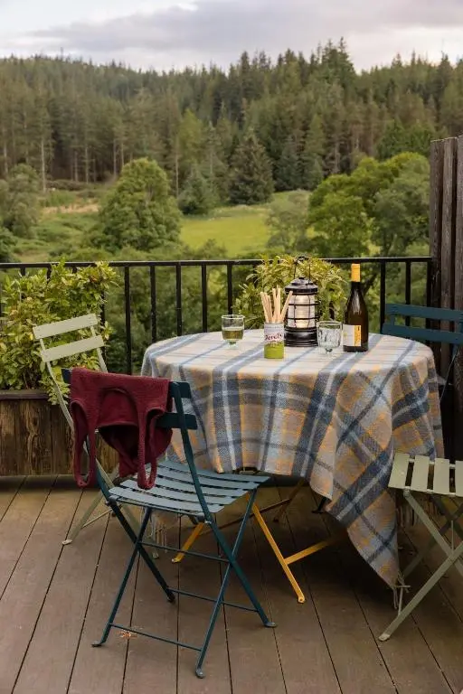 a table with two chairs and bottles of wine on a deck at The Hayloft in Banchory