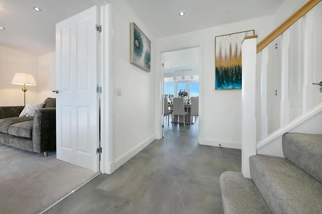 a living room with white walls and a hallway with stairs at Fern Place Villa - Grampian Lettings Ltd in West Cults