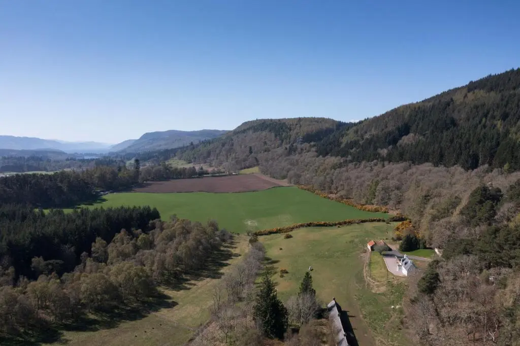an aerial view of a large green field in the mountains at Balnacraig Farmhouse in Inverness