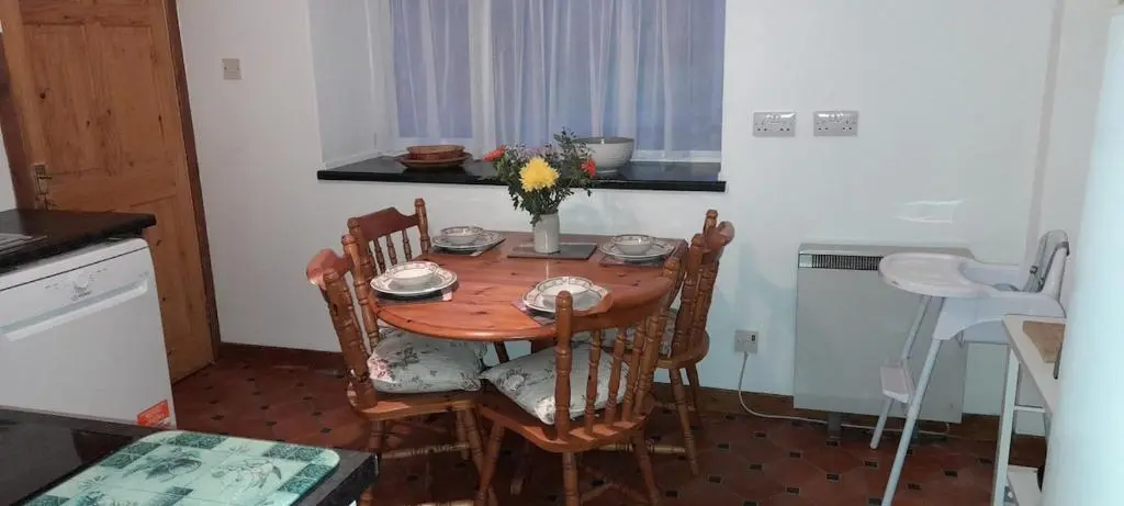 a wooden table with chairs and a vase of flowers at Sunnyside Cottage 2 Bedrooms 1 Bathroom 1 WC 2 Pets Welcome in Hilton of Cadboll