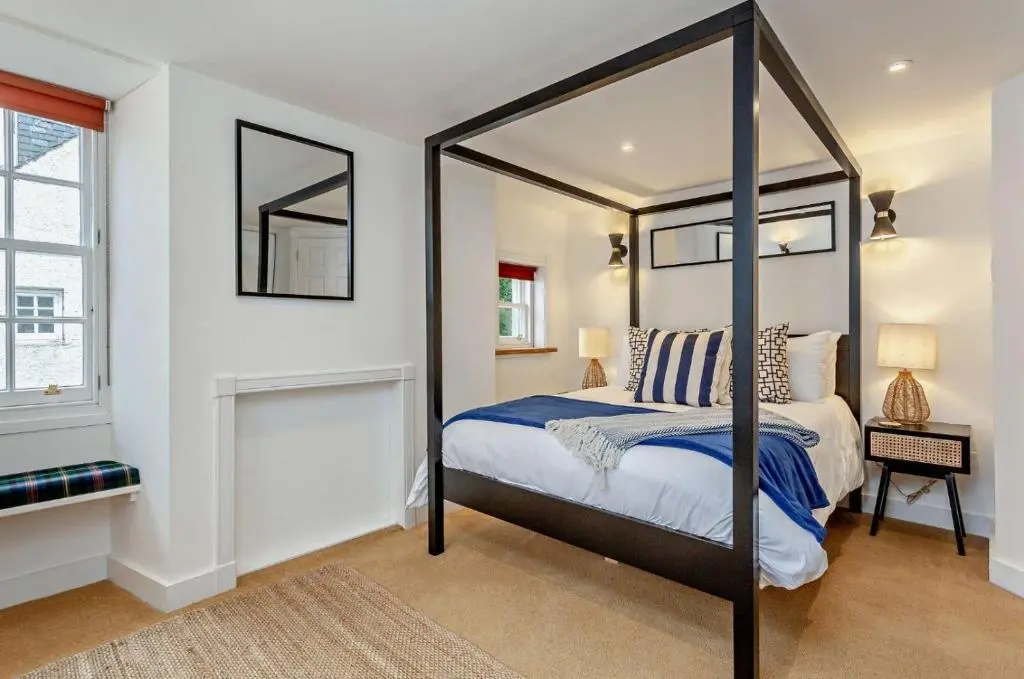 a bedroom with a canopy bed and a window at Jacobite's Retreat, 17th century cottage in the heart of Inverness in Inverness