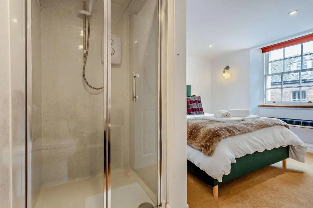 a bedroom with a shower and a bed in a room at Jacobite's Retreat, 17th century cottage in the heart of Inverness in Inverness