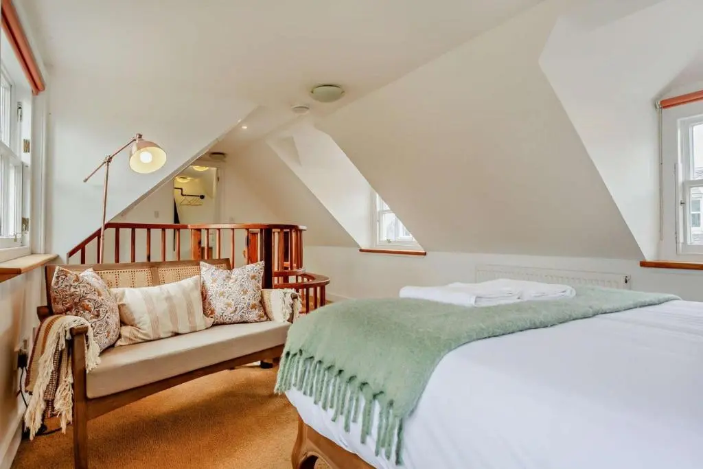 a bedroom with a bed and a chair in a attic at Jacobite's Retreat, 17th century cottage in the heart of Inverness in Inverness