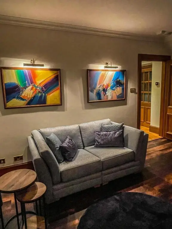 a living room with a couch and paintings on the wall at Cathedral Apartment in Inverness