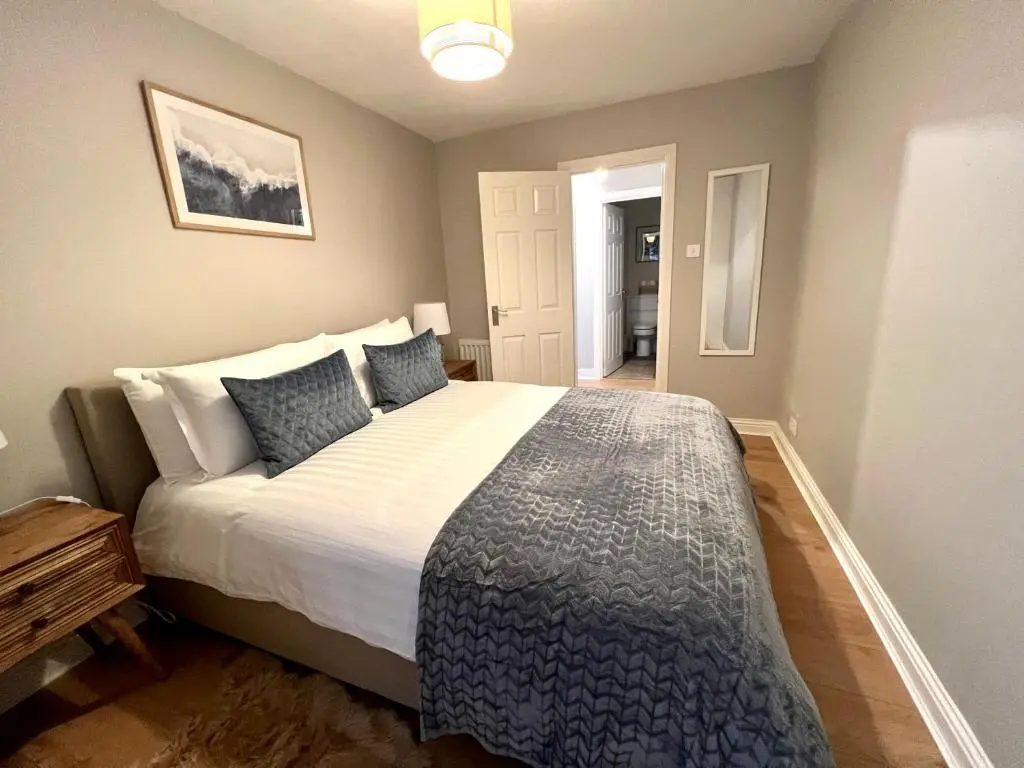 a bedroom with a large bed with blue pillows at Lossie Self-Catering Apartment in Lossiemouth