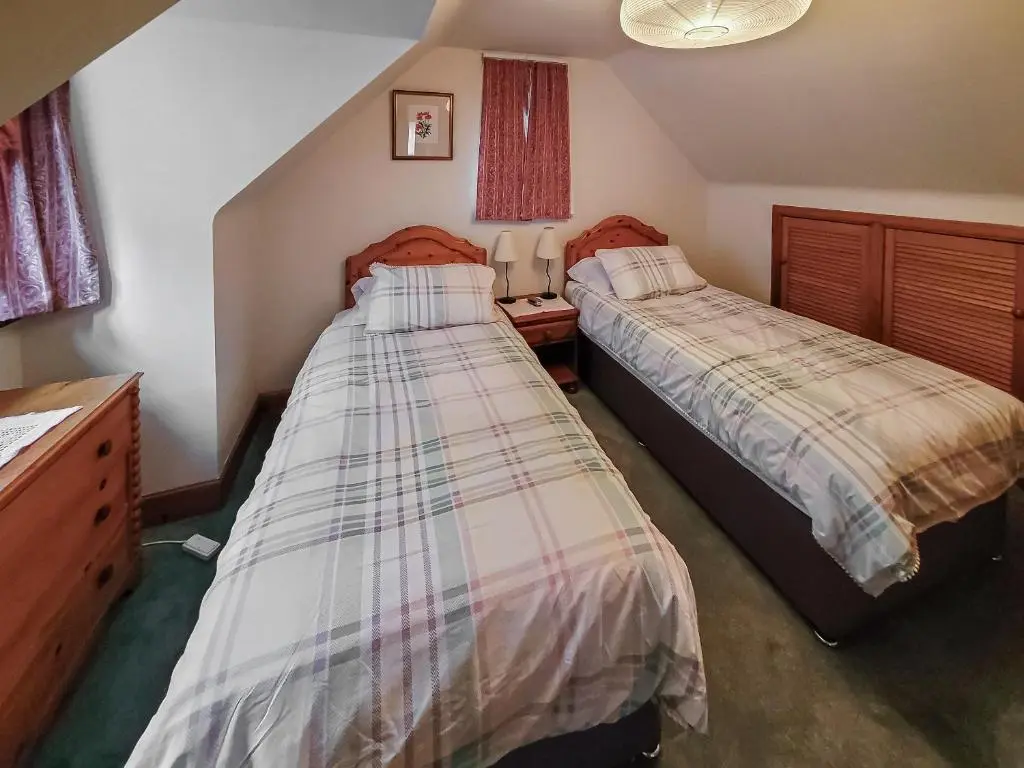 a bedroom with two beds and a dresser at South Lodge in Banchory