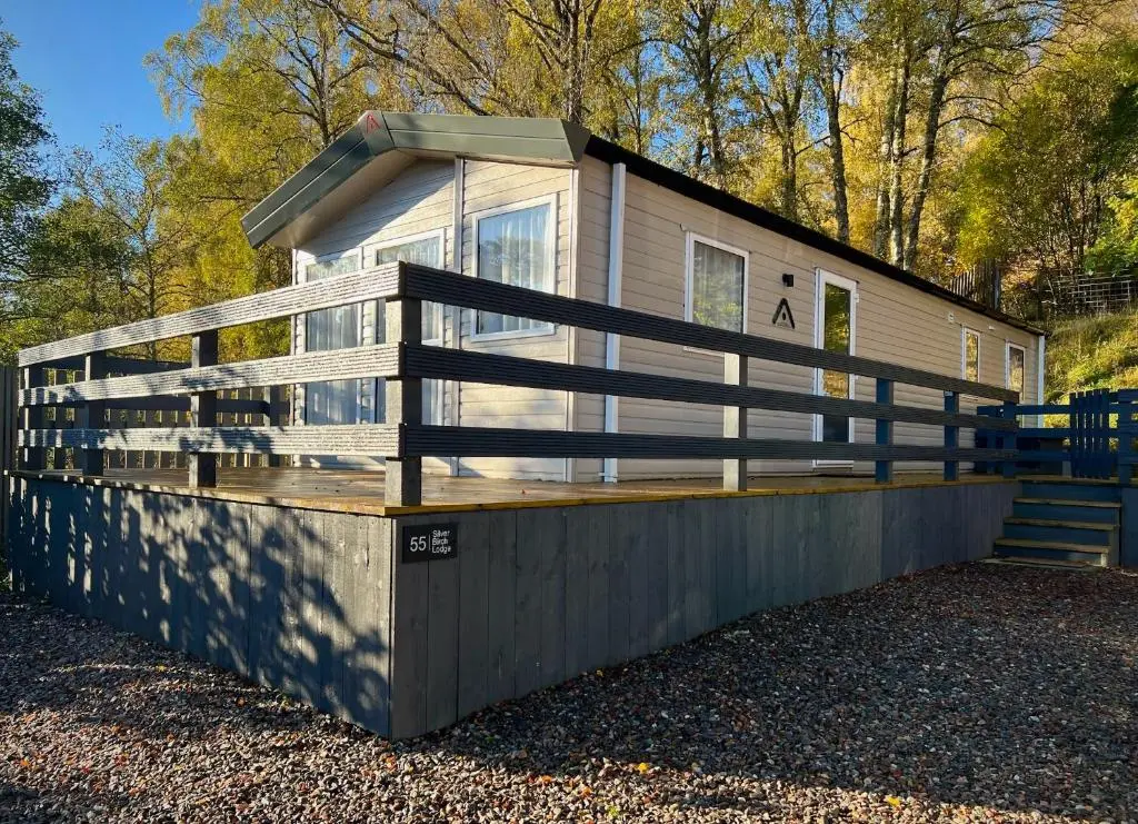 a house with a fence on the side of it at Silver Birch Lodge Aviemore in Aviemore