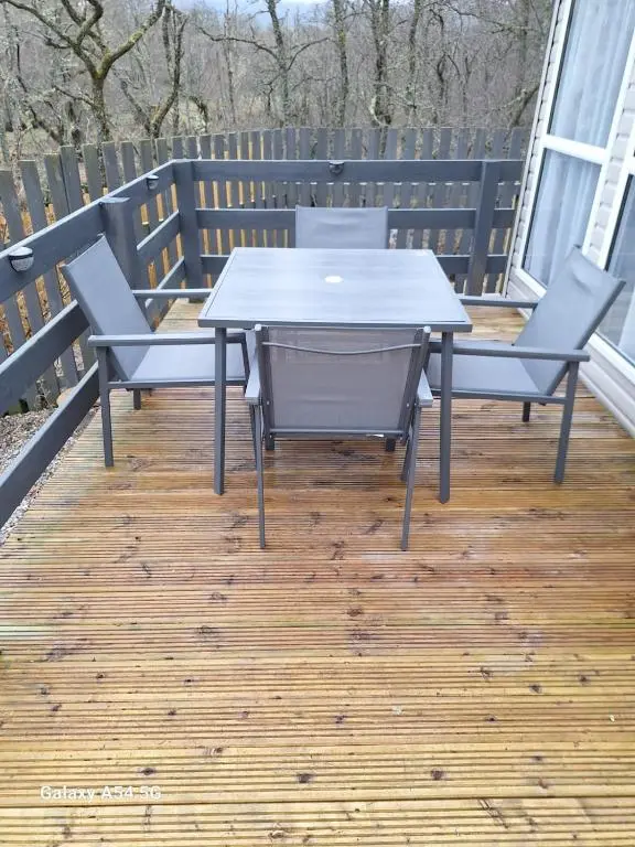 a table and two chairs on a deck with a table at Silver Birch Lodge Aviemore in Aviemore