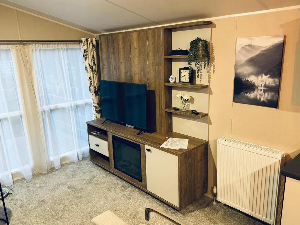 a living room with a flat screen tv on a desk at Silver Birch Lodge Aviemore in Aviemore
