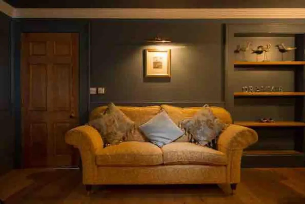 a living room with a yellow couch with pillows at The Millie Luxury Five Star with Sea View in Burghead