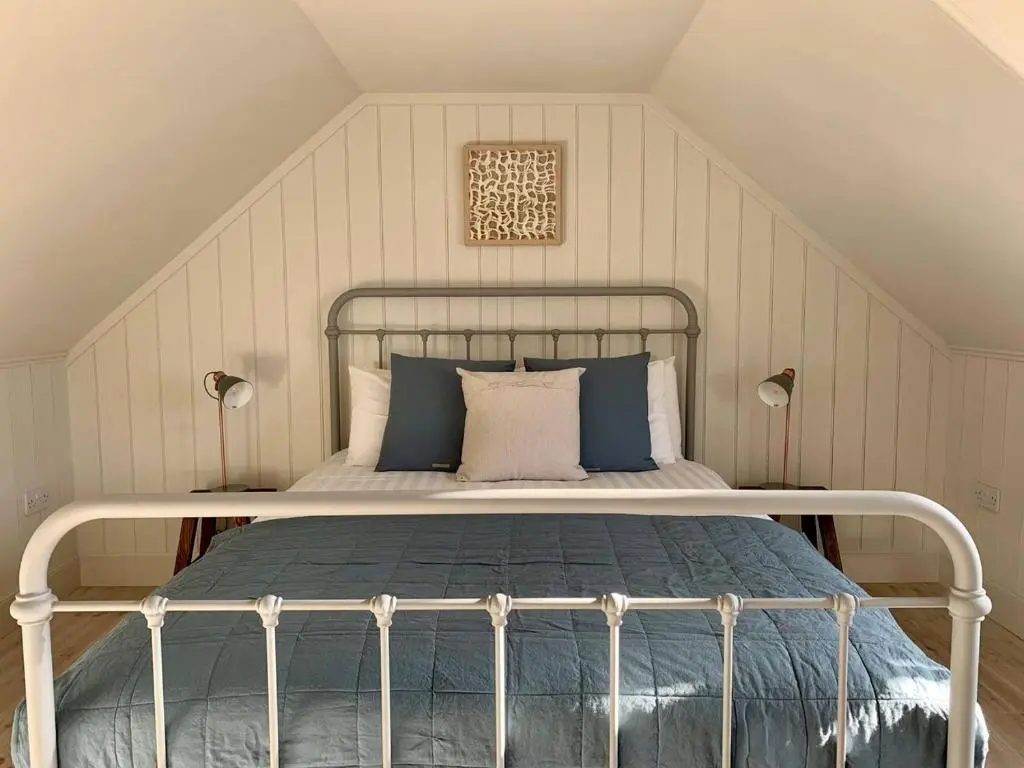 a bedroom with a bed with blue and white pillows at The Millie Luxury Five Star with Sea View in Burghead