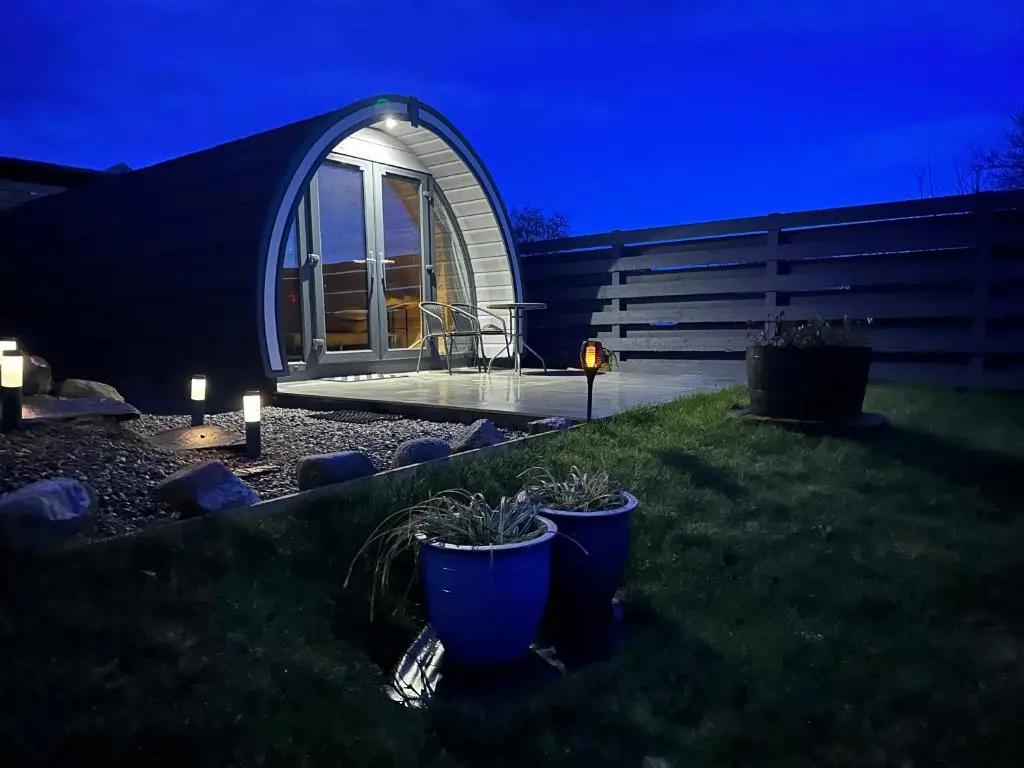 a glass house in a garden at night at Lochside Lodge Pod in Lairg