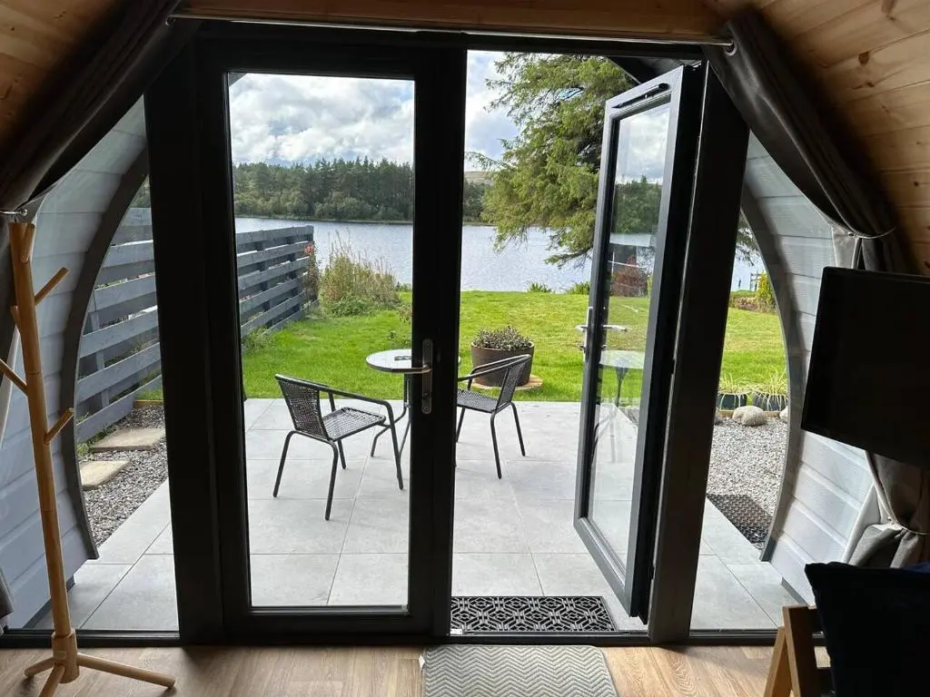 a door leading to a patio with a table and chairs at Lochside Lodge Pod in Lairg