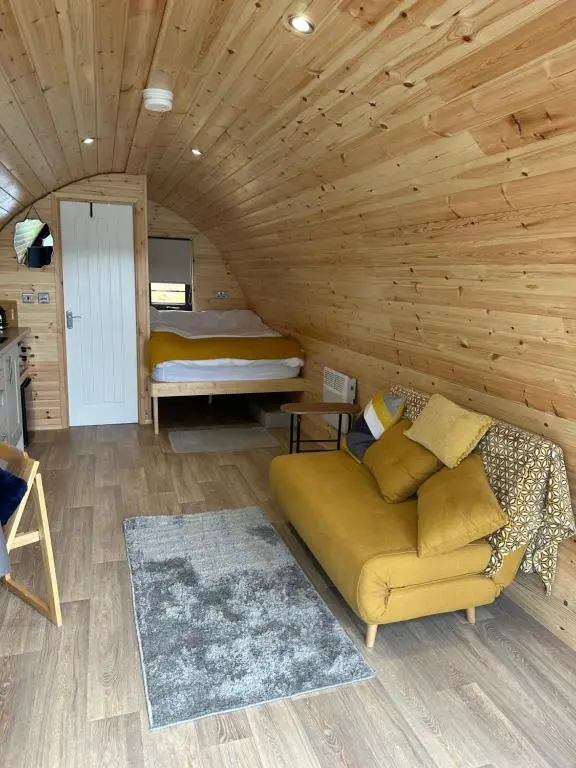 a living room with a couch in a log cabin at Lochside Lodge Pod in Lairg