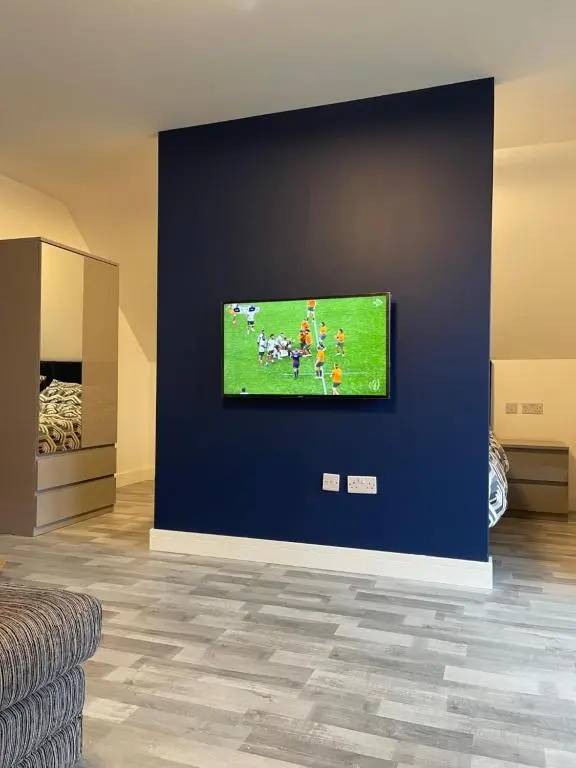 a television on a blue wall in a living room at Lochside Loft - Self Catering Apartment for 2 In a great location for Inverness Airport and both Cabot Highlands & Nairn Golf Courses in Inverness