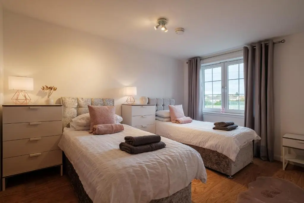 a bedroom with two beds and a window at Mackie Residence - SJA Stays - 3 Bed Apartment with parking in Westhill