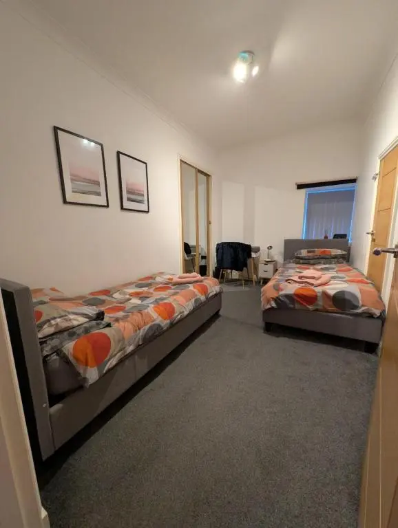 a bedroom with two beds and a chair in it at Cullen Holiday Home in Cullen