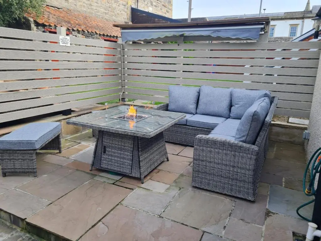 a patio with a table and wicker chairs and a table and bench at Cullen Holiday Home in Cullen