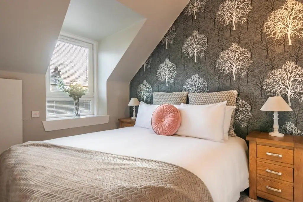 a bedroom with a large white bed with a patterned wall at Sweet Ness River Flat in Inverness