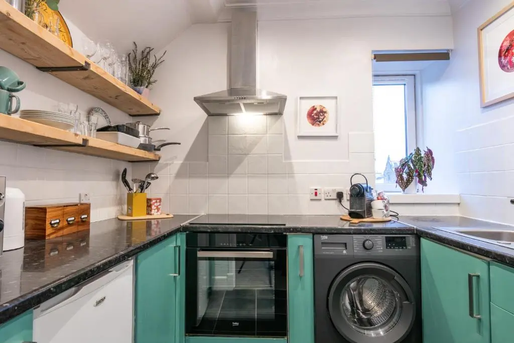 a kitchen with a washer and dryer in it at Sweet Ness River Flat in Inverness