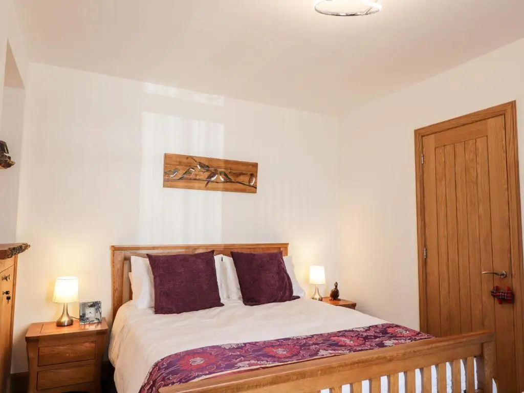 a bedroom with a bed with two night stands and two lamps at Corner Cottage in Buckie