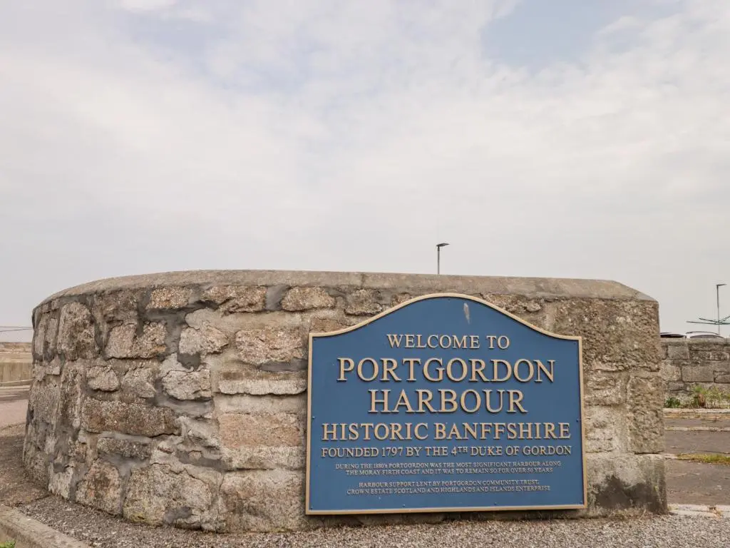 a sign on a stone wall with a welcome to portdoront harcourthistoric at Corner Cottage in Buckie