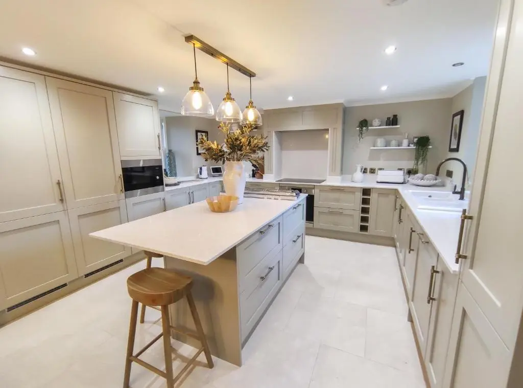 a kitchen with white cabinets and a island with a table at Cathedral House in Dornoch