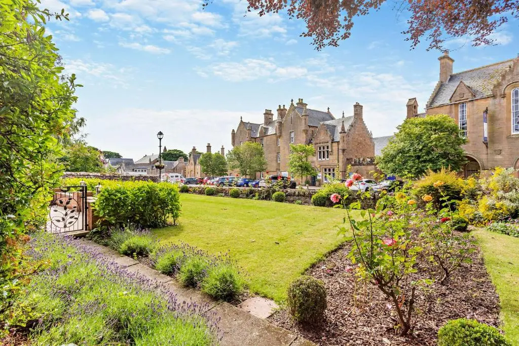 a garden in front of a row of buildings at Cathedral House in Dornoch