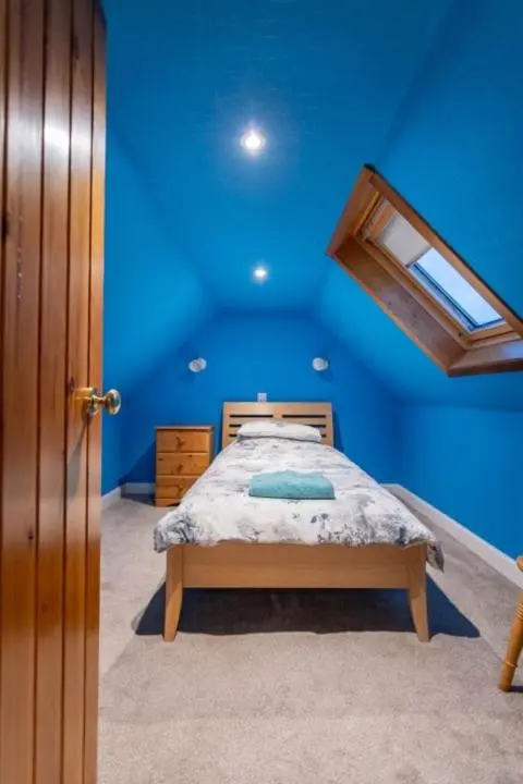 a blue bedroom with a bed and a window at 176 Marrell in Helmsdale